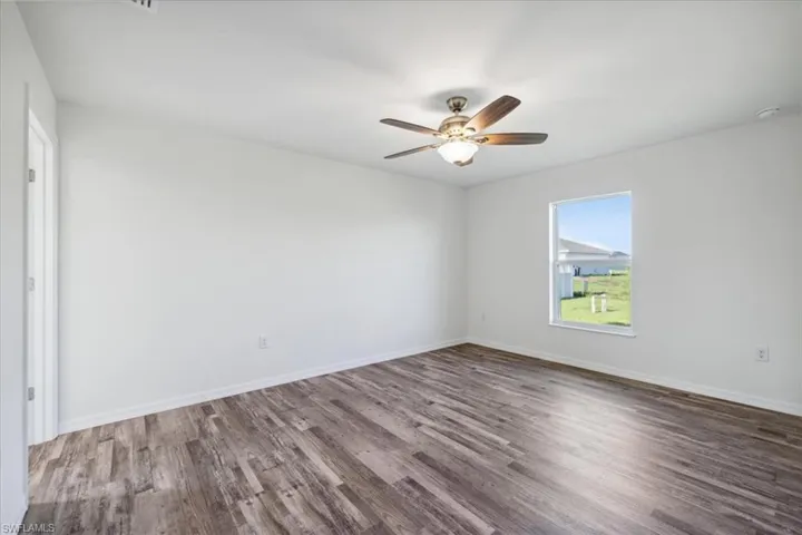 Unfurnished room featuring ceiling fan and dark wood-type flooring