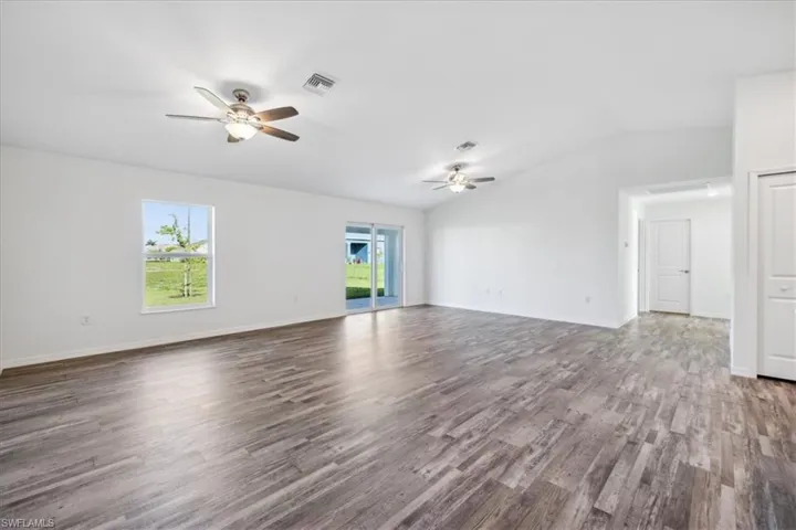Empty room with a wealth of natural light, ceiling fan, and dark hardwood / wood-style floors