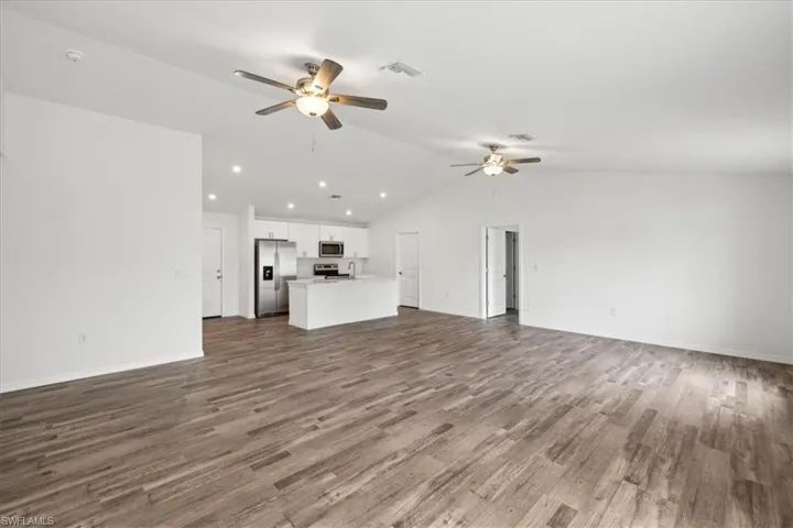 Unfurnished living room featuring lofted ceiling, ceiling fan, and hardwood / wood-style floors