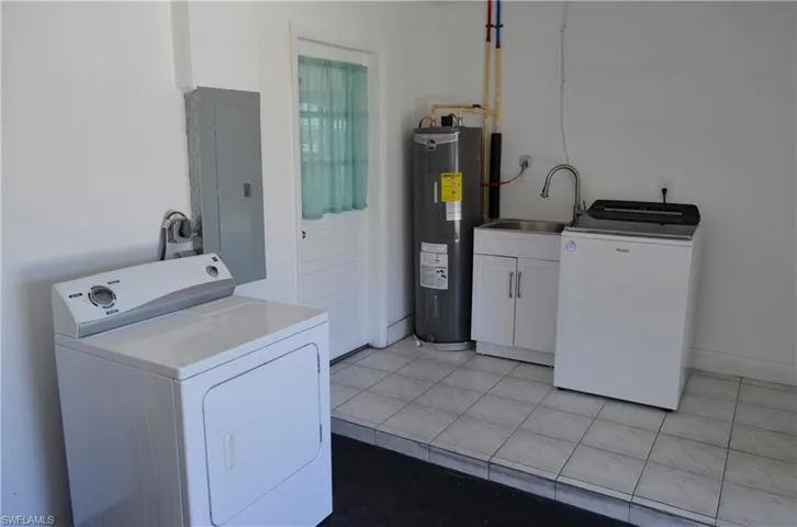 Laundry room with washer / clothes dryer, electric panel, water heater, and light tile patterned flooring