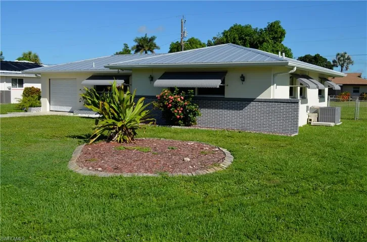 View of side of home with brick siding, a garage, and a metal roof