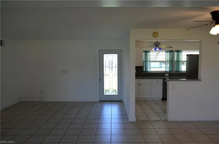 Kitchen with white cabinets, refrigerator, a ceiling fan, light stone countertops, and decorative backsplash