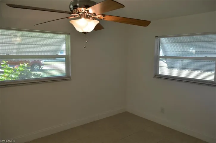 Empty room with healthy amount of natural light, light tile patterned floors, and a ceiling fan