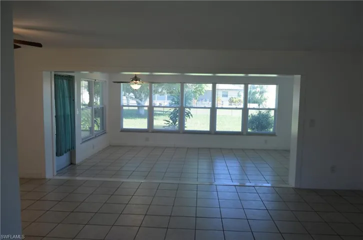 Unfurnished room featuring a ceiling fan, plenty of natural light, and light tile patterned floors