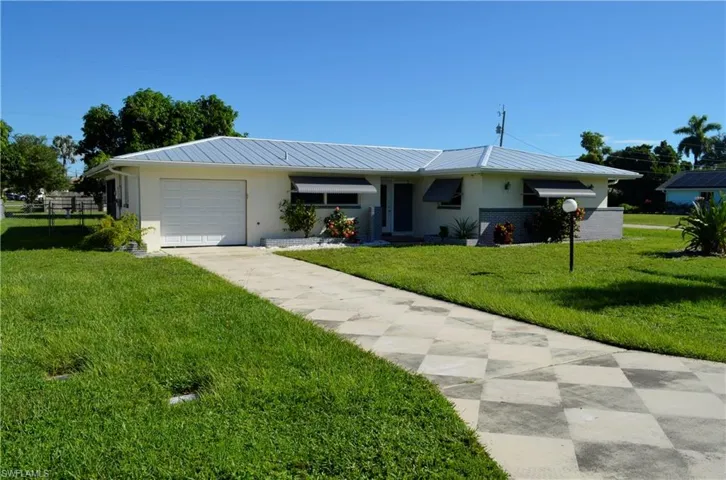 Single story home with a front yard, a metal roof, stucco siding, and a garage