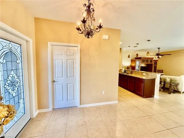 Tiled entryway with chandelier, stained glass entry door.