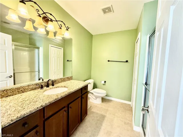 Bathroom featuring tile floors, vanity, an enclosed shower, and toilet