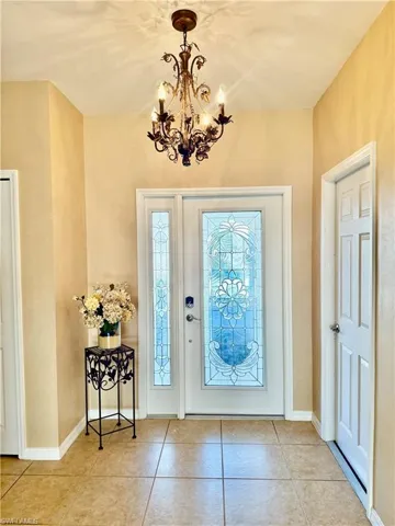 Foyer entrance featuring, stained glass door, light tile floors and chandelier