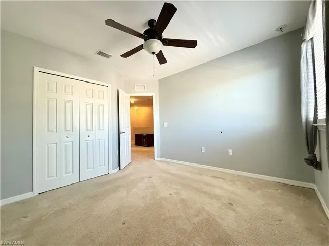 Unfurnished bedroom with ceiling fan, a closet, and carpet