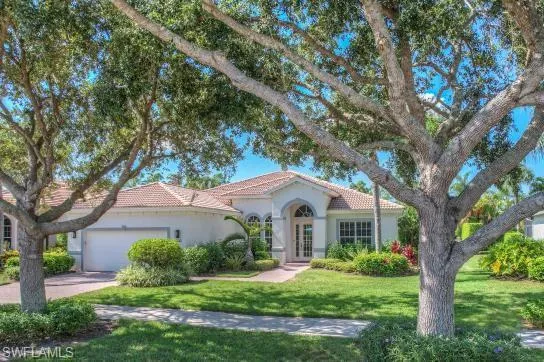 Mediterranean / spanish home with a tile roof, a front yard, a garage, and stucco siding