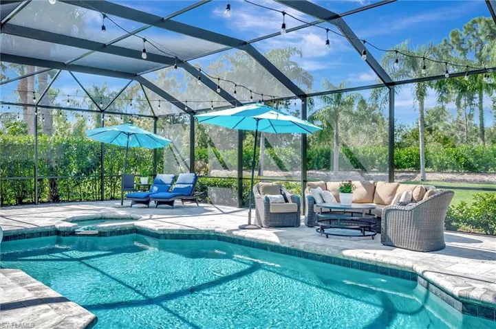 View of pool with glass enclosure, outdoor lounge area, a sunroom, and a pool with connected hot tub