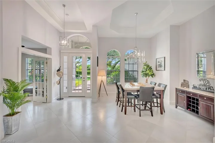 Dining room with a chandelier, plenty of natural light, a towering ceiling, and light tile patterned flooring