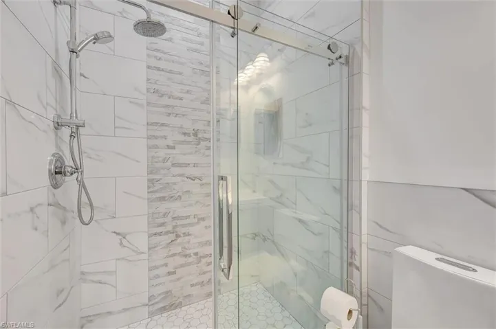 Full bathroom featuring a marble finish shower and toilet