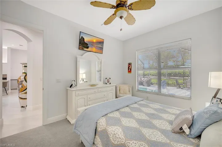 Bedroom with arched walkways, light carpet, and a ceiling fan