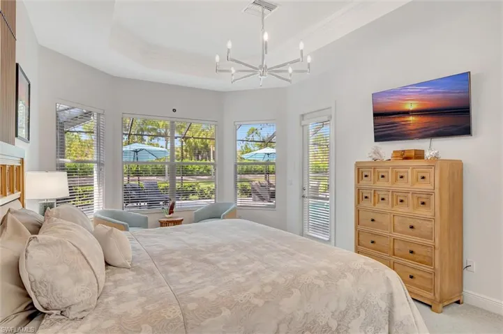 Bedroom featuring access to outside, carpet flooring, crown molding, a raised ceiling, and a chandelier