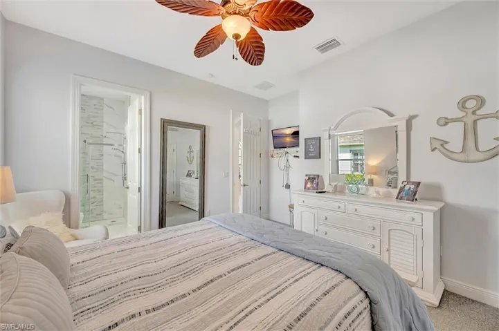 Bedroom with light carpet, ensuite bath, and a ceiling fan