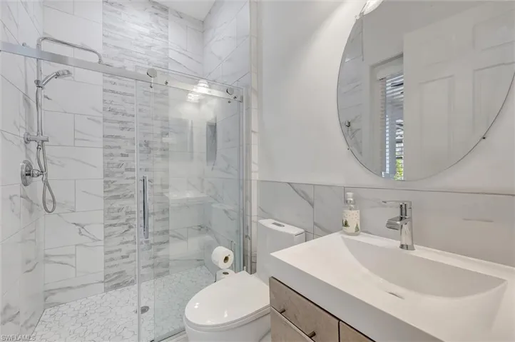 Bathroom with vanity, a shower stall, and tile walls