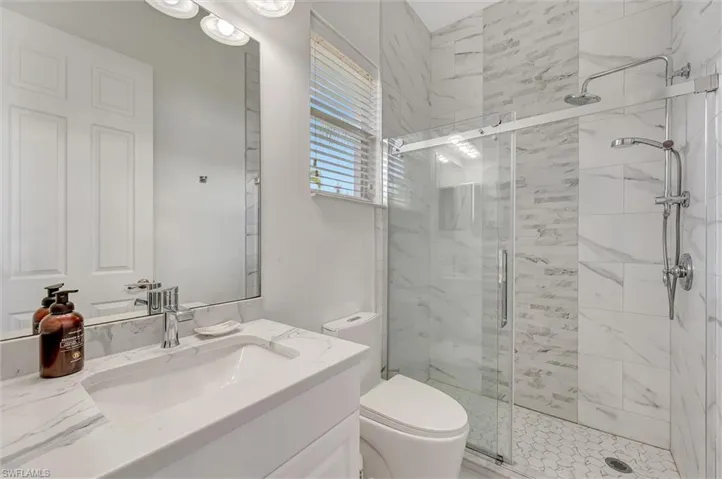 Full bath with a marble finish shower and vanity