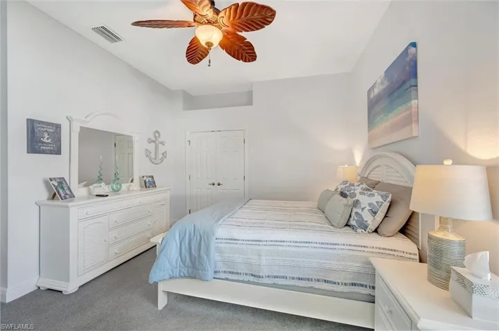 Carpeted bedroom featuring ceiling fan and a closet