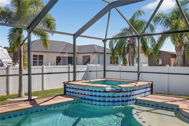 View of pool with a lanai, a fenced backyard, a sunroom, and a pool with connected hot tub