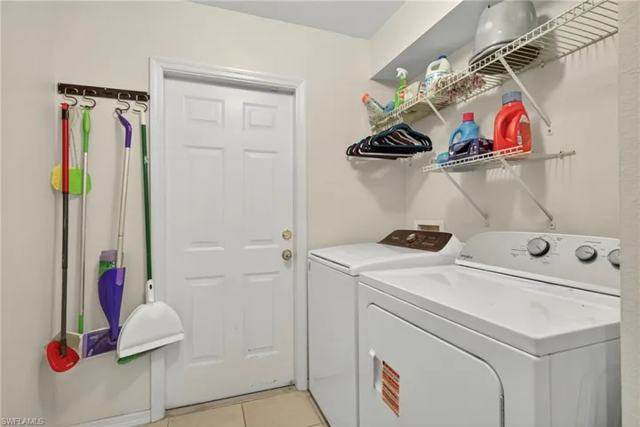 Laundry room with light tile patterned floors and washing machine and clothes dryer