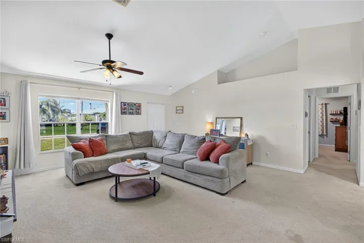 Living room with light colored carpet, high vaulted ceiling, and ceiling fan