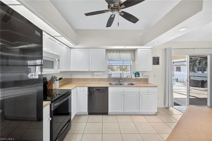 Kitchen with black appliances, light countertops, white cabinetry, light tile patterned floors, and recessed lighting