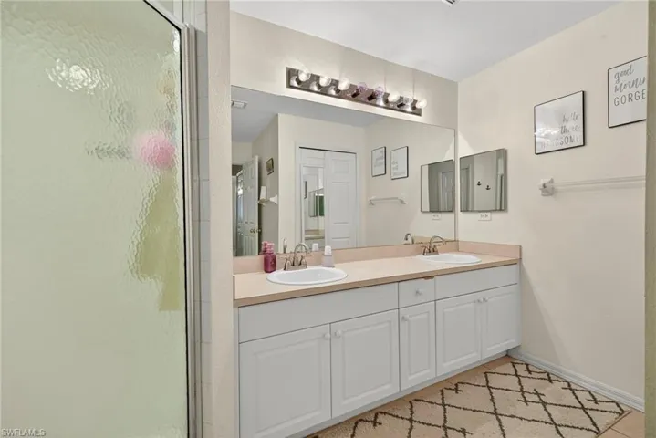 Full bathroom featuring double vanity, a shower stall, and light tile patterned floors