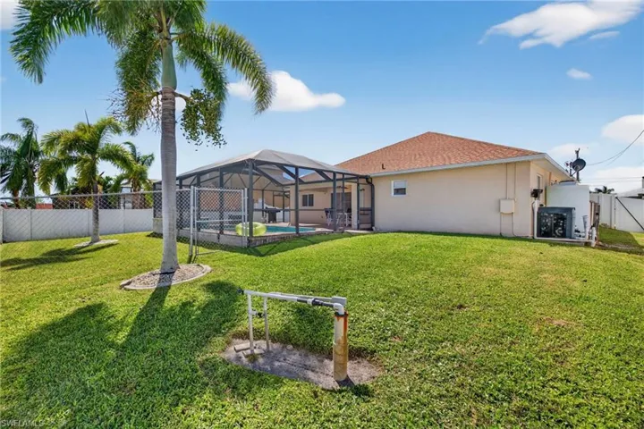 Rear view of property featuring a fenced backyard, glass enclosure, a patio area, and a swimming pool