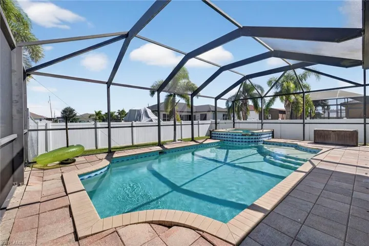 View of pool with glass enclosure, a fenced backyard, a sunroom, and a pool with connected hot tub