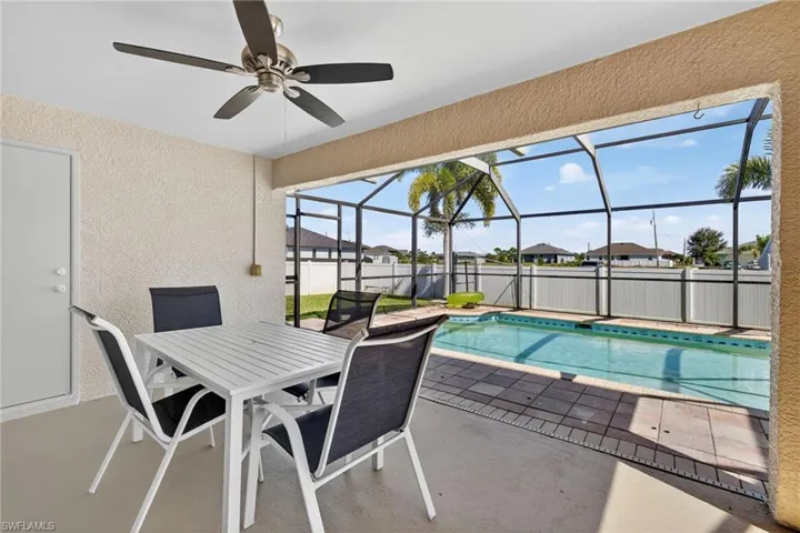 View of pool with a patio, a sunroom, glass enclosure, outdoor dining space, and a ceiling fan