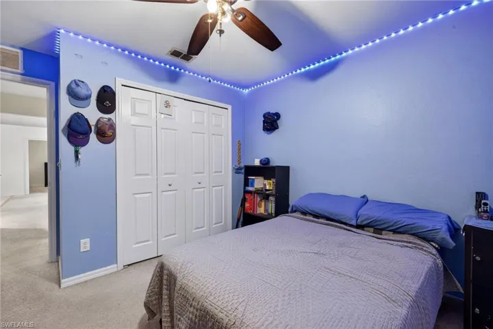 Carpeted bedroom with a ceiling fan and a closet