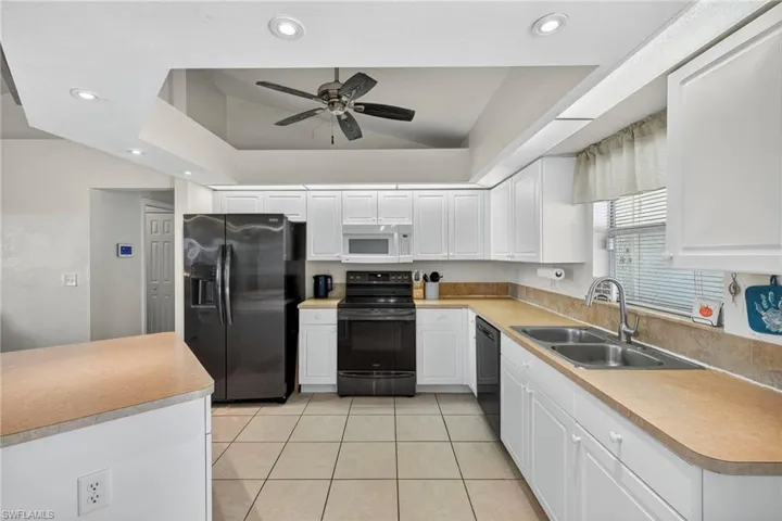 Kitchen featuring black appliances, white cabinetry, light tile patterned flooring, recessed lighting, and light countertops