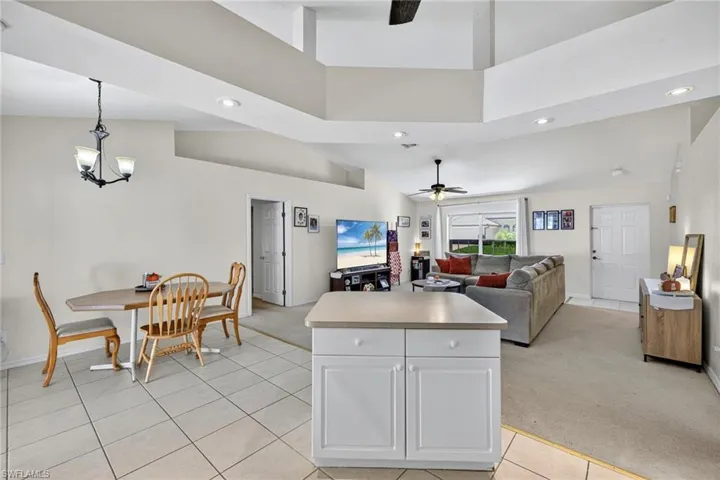 Kitchen featuring recessed lighting, open floor plan, decorative light fixtures, white cabinetry, and light colored carpet