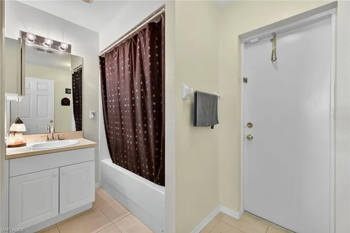 Bathroom with light tile patterned flooring, vanity, and shower / bath combo with shower curtain