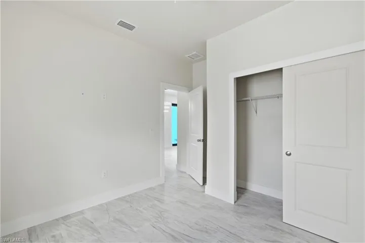 Unfurnished bedroom with a closet and light marble finish flooring