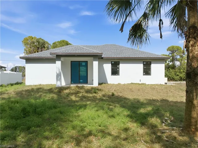 Rear view of property with stucco siding and roof with shingles