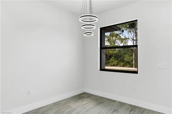Spare room with baseboards and suspended lighting