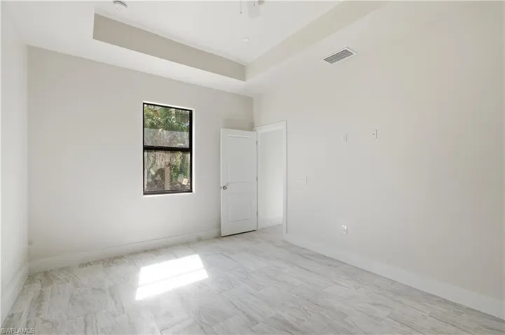 Spare room featuring a tray ceiling and baseboards