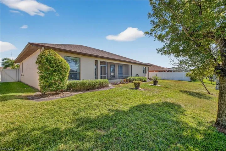 Rear view showcasing stucco siding, new privacy fence (2023), and spacious backyard on the canal.