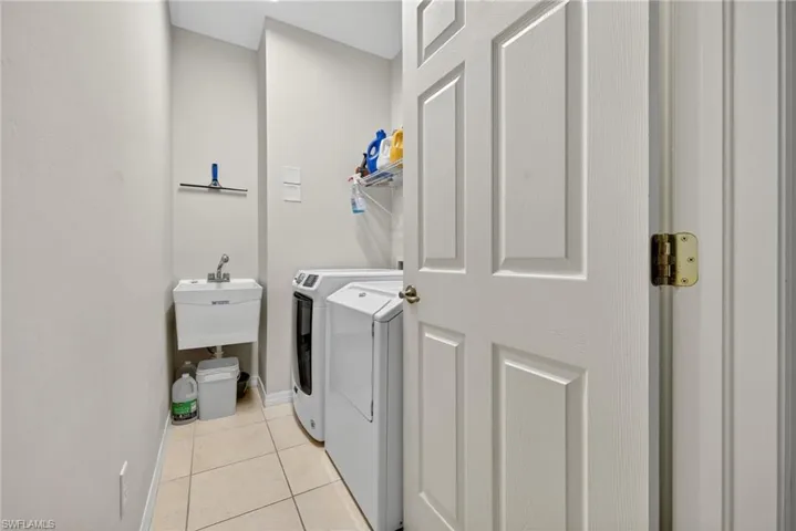 Dedicated laundry room with washer, dryer, and light tile flooring.