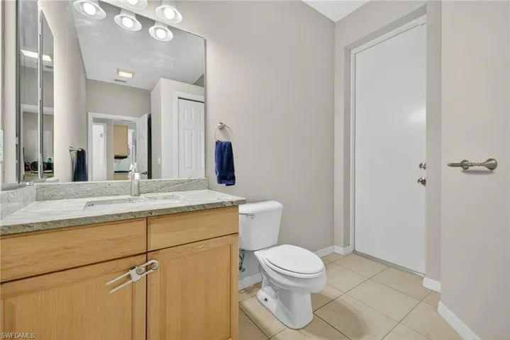 Convenient guest half bath with vanity and light tile flooring.