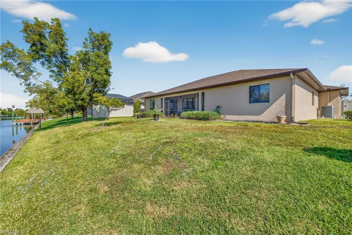 Back of home with stucco siding, privacy fence (2023), and canal frontage.