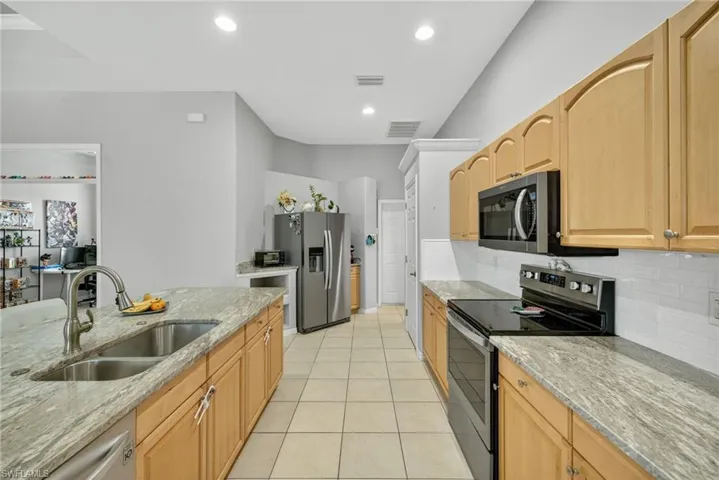 Kitchen featuring stainless-steel appliances (2019), Level 4 River White granite, decorative backsplash, warm wood cabinetry, and tile flooring.