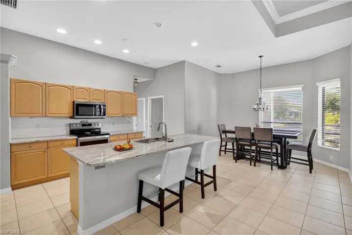 Breakfast bar with pendant lighting, Level 4 River White granite, stainless-steel appliances (2019), and decorative backsplash.