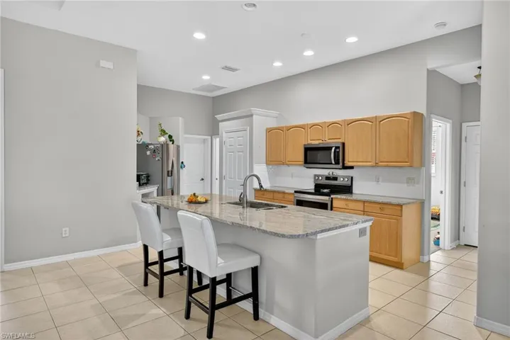 Kitchen bar seating with stainless-steel appliances (2019), Level 4 River White granite, and decorative backsplash. Perfect for casual dining.