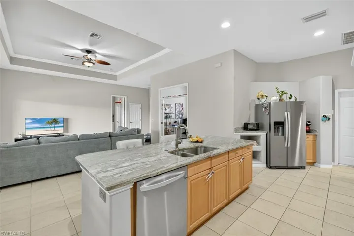 Spacious kitchen with Level 4 River White granite countertops, stainless-steel appliances (2019), tray ceiling, and light tile flooring.