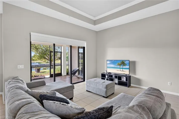 Bright open living room with light tile flooring and crown molding. A comfortable everyday gathering space.