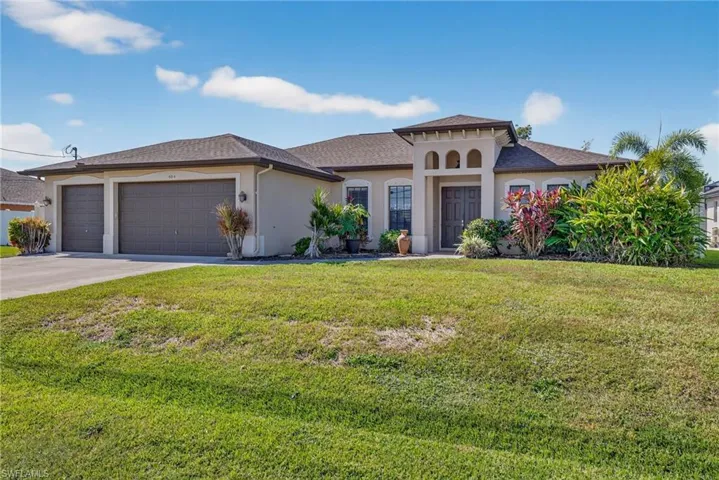 Tundra-built custom home with an oversized 3-car garage, Mediterranean-style stucco exterior, tiled front porch, lush landscaping, and extended concrete driveway. Gutters around the entire home.