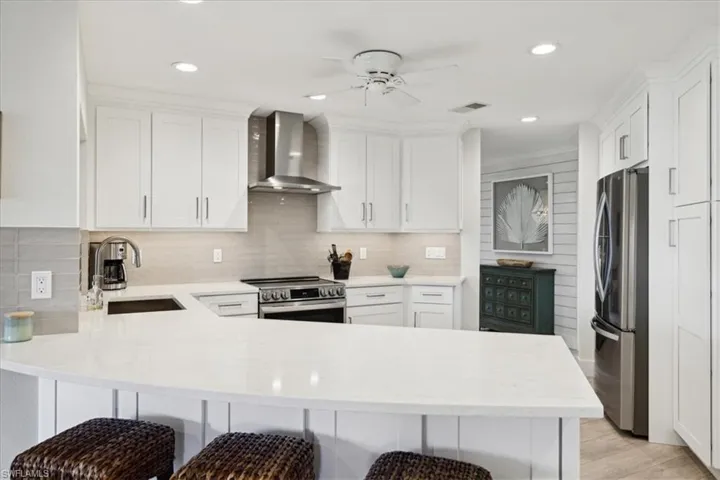 Kitchen featuring a breakfast bar, Large sink, Eating Bar, range hood and stainless steel appliances